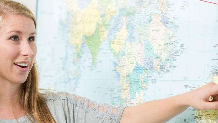 女学生指着墙上大小的国际地图.